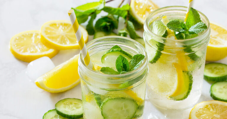 Refreshing summer drink with lemon and cucumber on a background of stone. The concept of eating vegetarians, fresh vitamins, a homemade refreshing fruit drink.